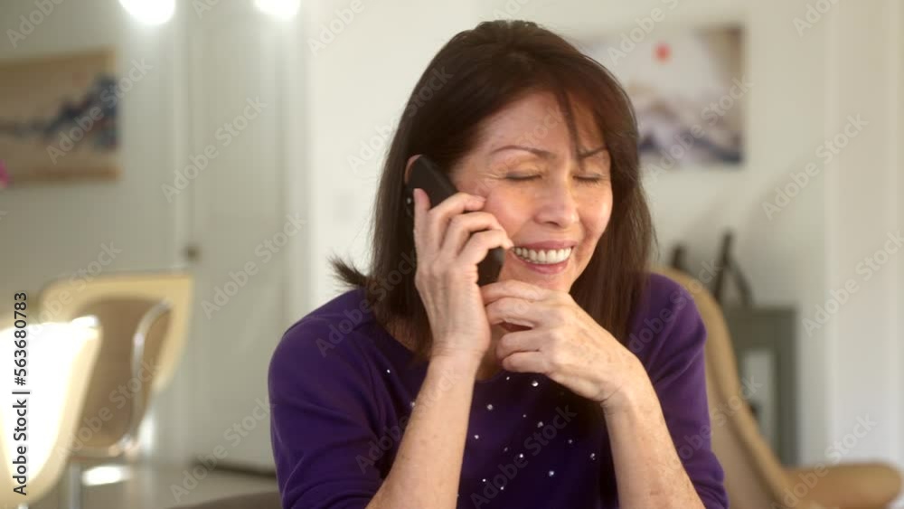 Attractive woman looking at camera, smiling and waving at camera on mobile phone at home kitchen table Attractive woman looking at camera, smiling and waving at camera on mobile phone at home kitchen table