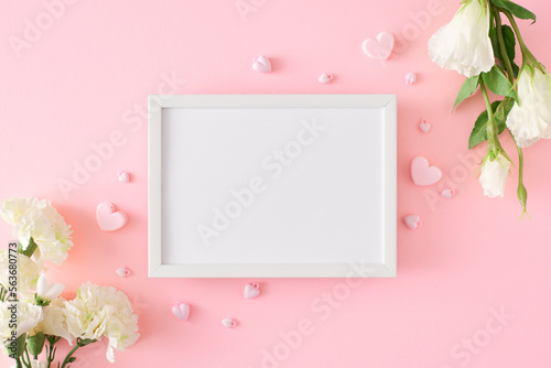 Hello spring concept. Flat lay photo of white spring flowers and hearts on pastel pink background and frame in the middle. 8-march holiday card idea. © Goncharuk film