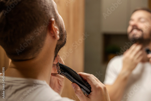 Close up of a bearded man trimming his beard in bathroom.