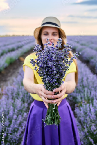Young beautiful woman in hat holding a bouquet of lavender flowers