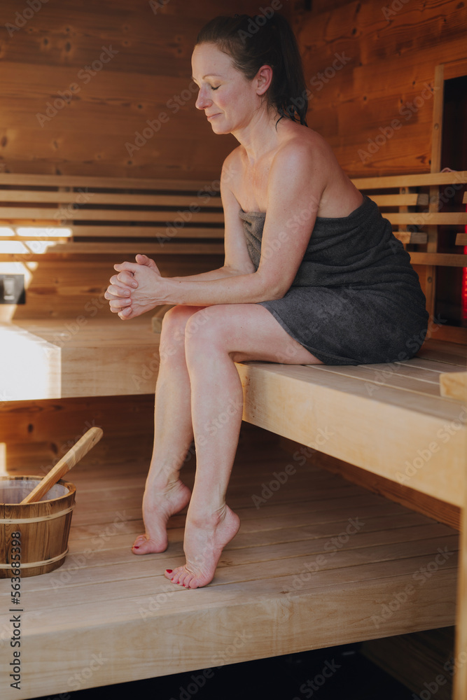 Naklejka premium Frau sitzt in finnischer Sauna