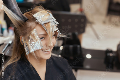 Hair stylist makes bouffant using comb on thin strands. Shatush technique for hair lightening.