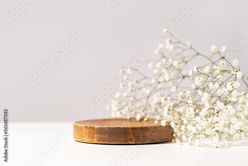 Beauty cosmetic product presentation scene made with a wooden plate and wild flowers. Summer mood background. Front view.