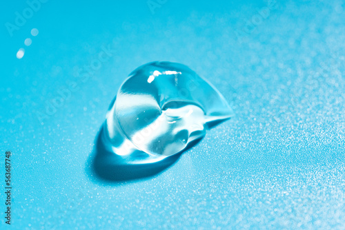 Liquid cosmetic gel drop, hyaluronic acid gel on a blue background.