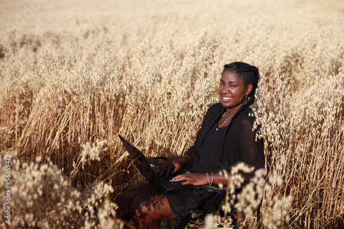 young african woman working with laptop in summer field