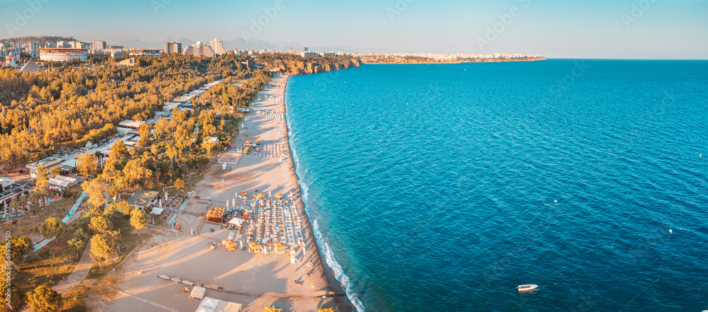 Obraz premium Aerial drone view of scenic and popular Konyaalti beach in Antalya resort town. Majestic mountains with haze in the background. Vacation and holiday in Turkey