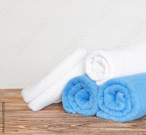 Rolled white and blue bath towels on a wooden table
