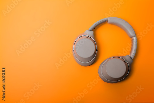Light gray wireless over-ear headphones on an orange background. Headphones for playing games or listening to music. Noise canceling headphones. Top view. Copy space.
