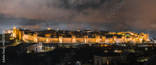 Obraz na plátne Panoramic view of the old town of Ávila, Spain, surrounded by a medieval wall, lit up during a cold cloudy winter night