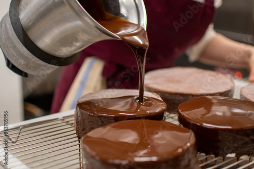 Pastry chef glazing chocolate cakes