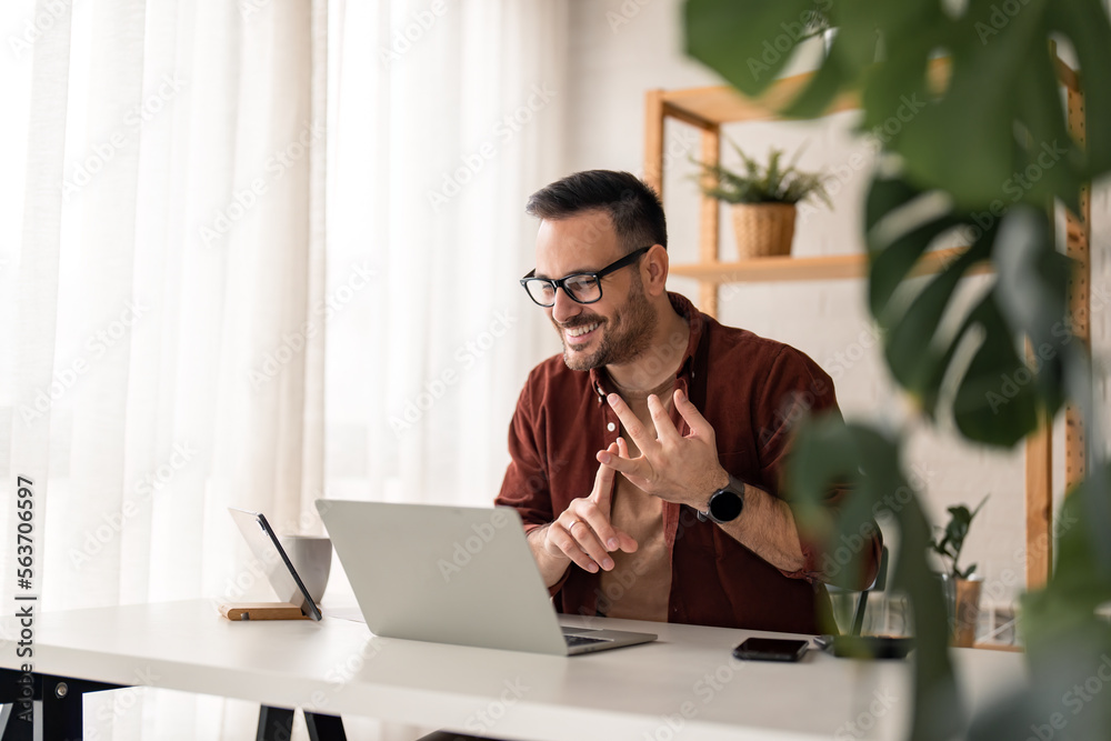 © Dorde - Cheerful young businessman employee, HR manager having remote online work hybrid meeting or distance job interview, gesturing with hands during virtual video conference call in home office.