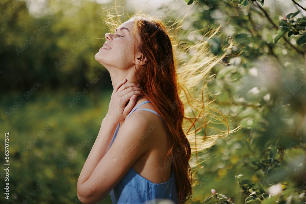 Woman with a beautiful smile with teeth and long hair in the spring sunset in nature in the park near the flowering trees happiness Woman with a beautiful smile with teeth and long hair in the spring sunset in nature in the park near the flowering trees happiness