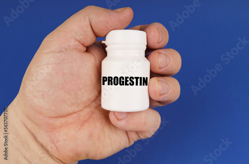 On a blue background in the hands of a man is a white jar with the inscription - Progestin photo