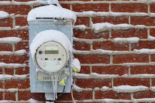 Electricity meter outside a building in winter, with snow and ice
