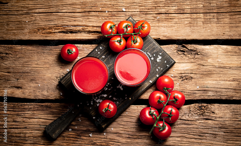 Glasses with tomato juice on a wooden cutting board. Glasses with tomato juice on a wooden cutting board.