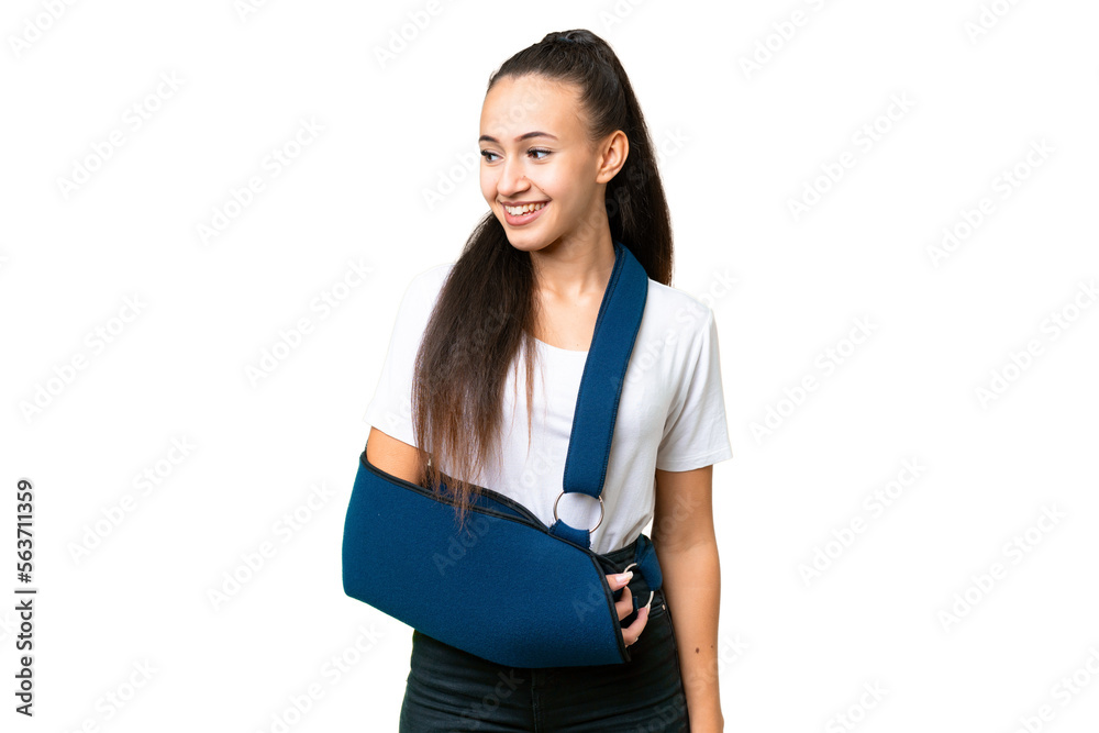 Young Arabian woman with broken arm and wearing a sling over isolated chroma key background looking to the side and smiling Young Arabian woman with broken arm and wearing a sling over isolated chroma key background looking to the side and smiling