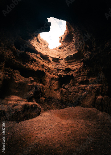 A view of the inside of Cave with beautiful natural sunlight from the  top throught the hole. Moody and dark empty cave with soft light.
