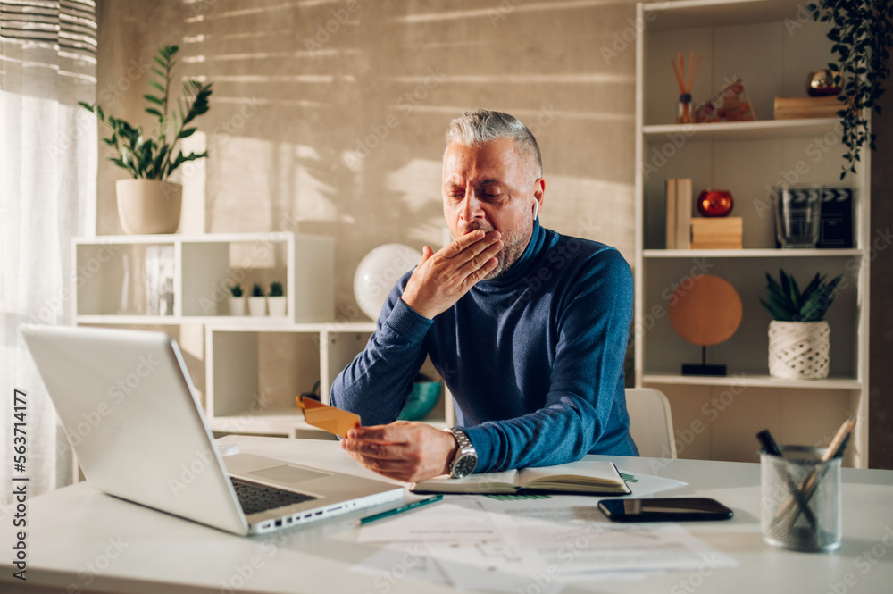 Middle aged man online shopping with laptop and a credit card at home Middle aged man online shopping with laptop and a credit card at home