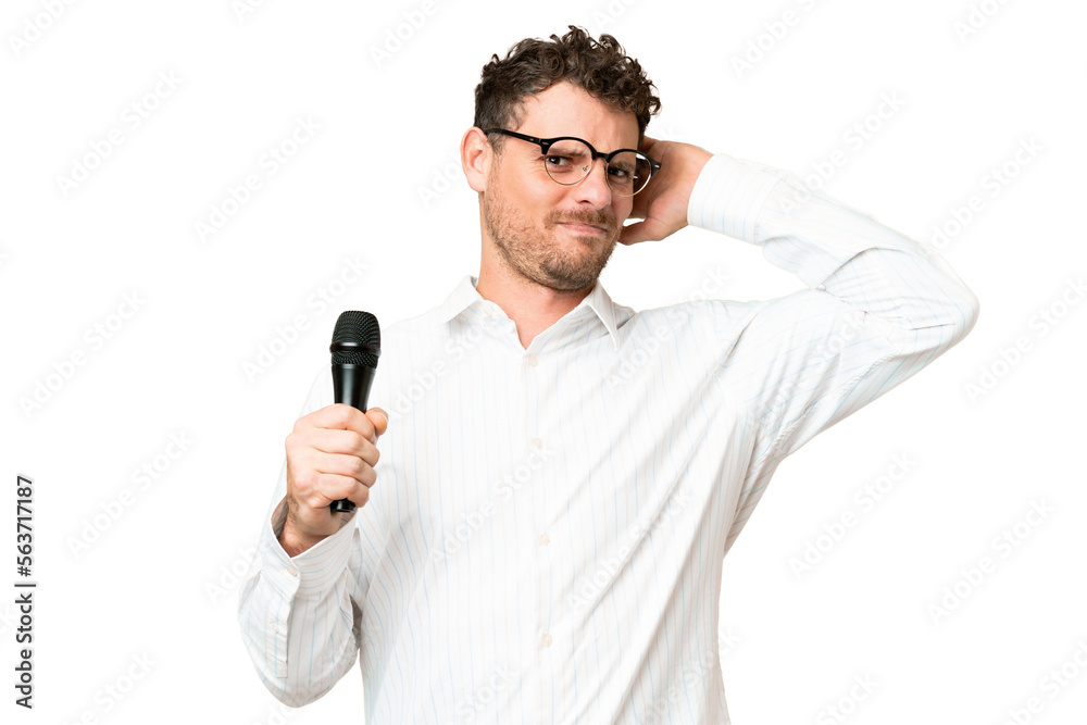 Brazilian man picking up a microphone over isolated chroma key background having doubts