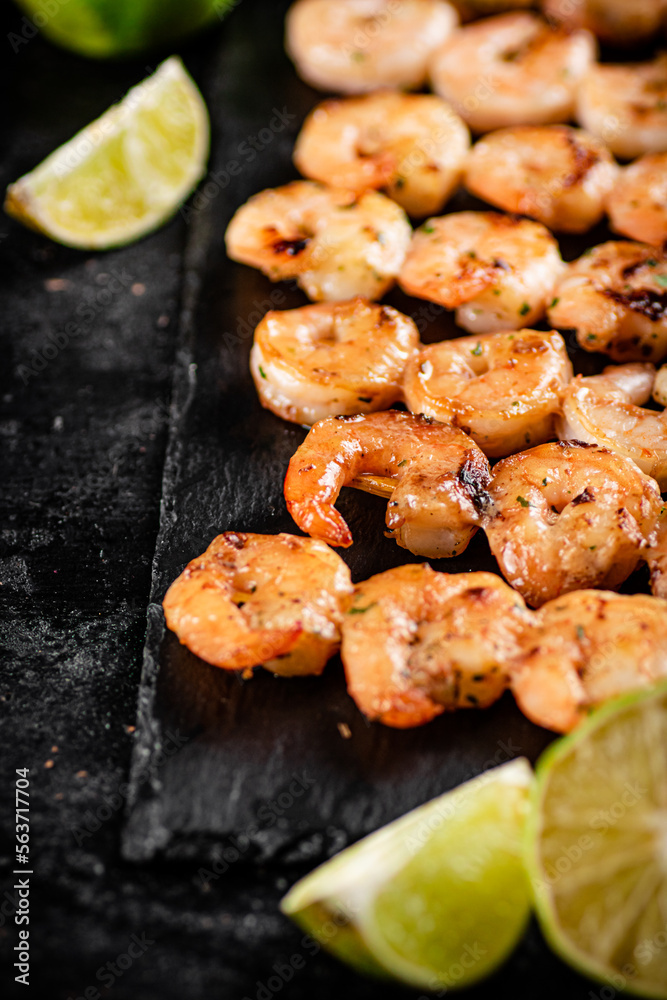 Grilled shrimp on a stone board with pieces of lime. Grilled shrimp on a stone board with pieces of lime.