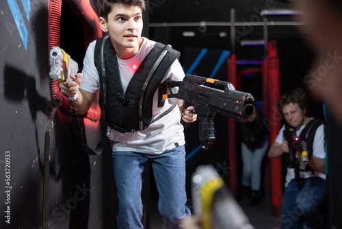 Emotional young man with laser pistol playing laser tag with friends on dark labyrinth © JackF