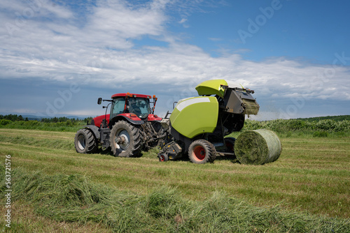 Baling hay baling or pressing hay pressing with hay baler in the fields on farm.  photo