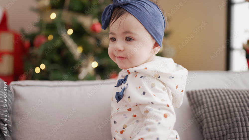 Adorable toddler smiling confident standing on sofa by christmas tree at home Adorable toddler smiling confident standing on sofa by christmas tree at home