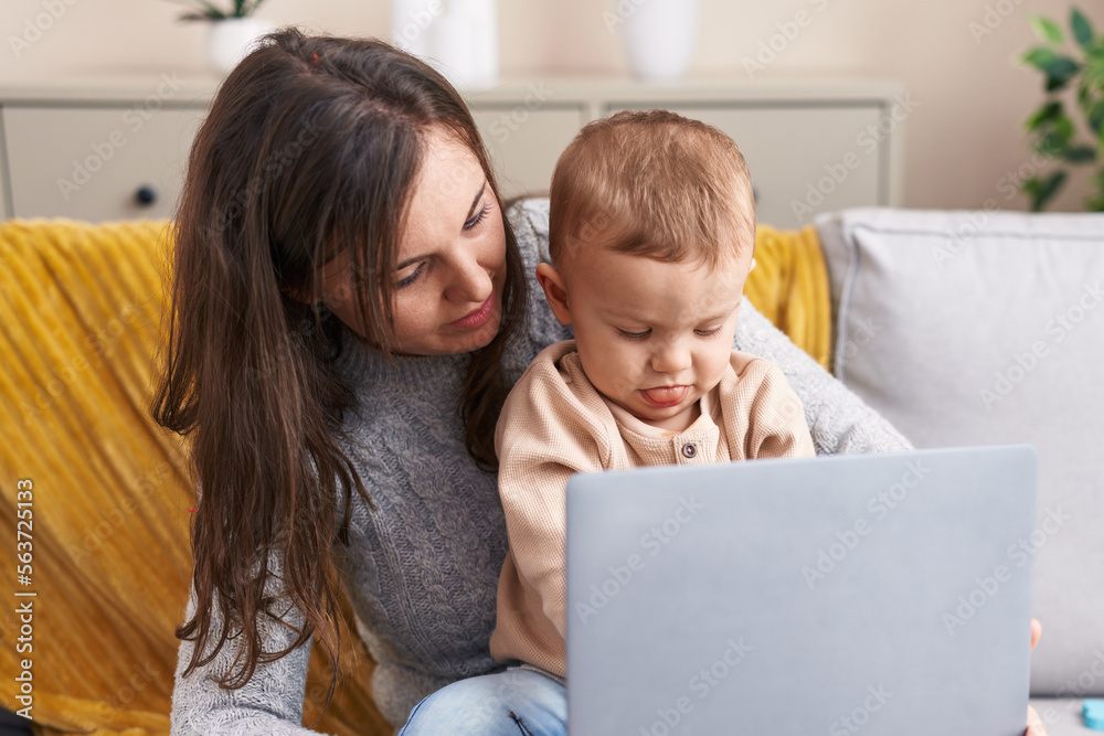 Mother and son using laptop sitting on sofa at home Mother and son using laptop sitting on sofa at home