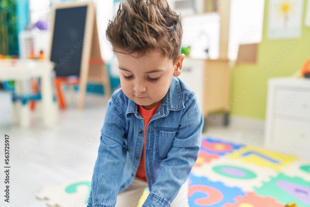 Adorable hispanic toddler standing with relaxed expression at kindergarten