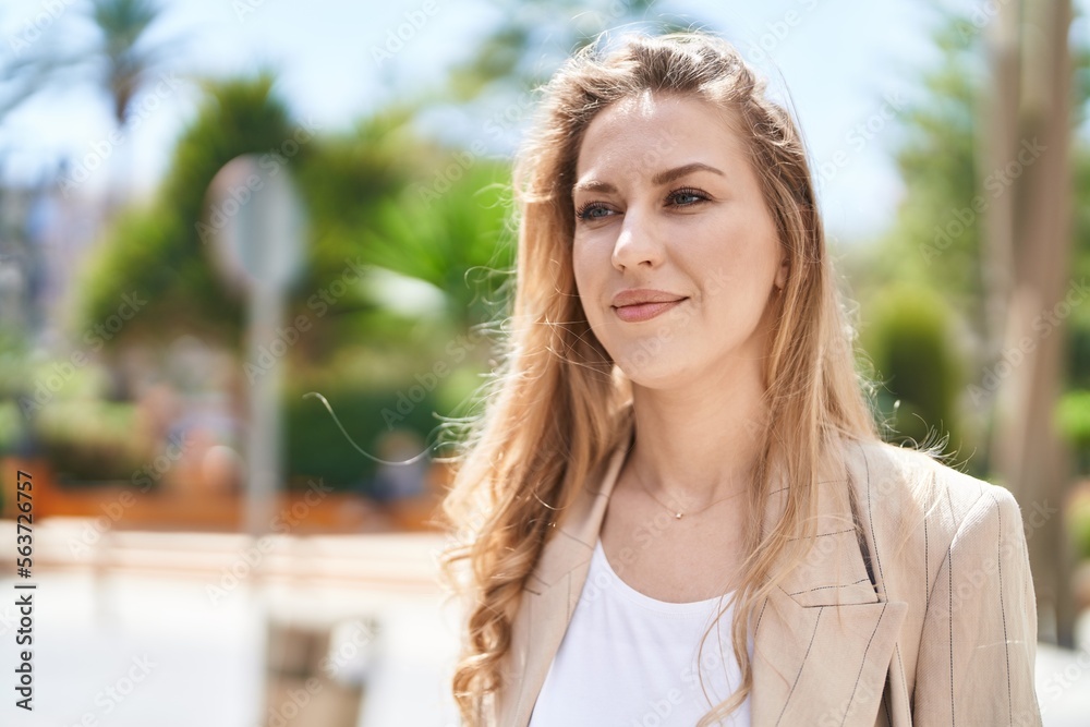 Young blonde woman smiling confident standing at park
