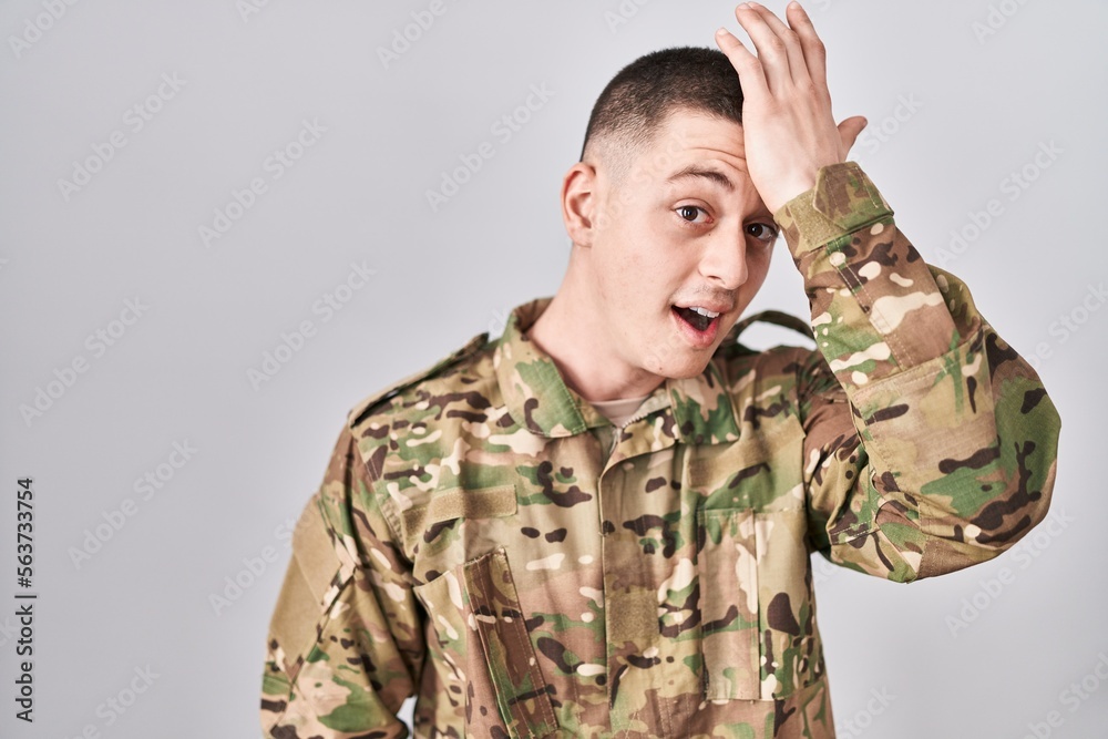 Young man wearing camouflage army uniform surprised with hand on head for mistake, remember error. forgot, bad memory concept. Young man wearing camouflage army uniform surprised with hand on head for mistake, remember error. forgot, bad memory concept.