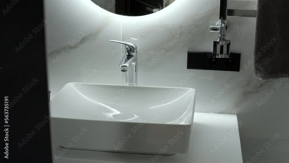 Modern bathroom with a shower area and bath tub including a wall mirror beside a fancy plant near a tap and sink over the wooden counter and dark cupboard