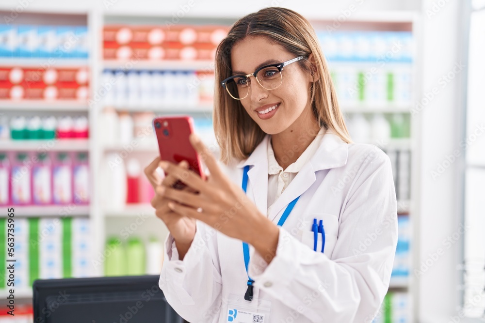 Young blonde woman pharmacist using smartphone working at pharmacy Young blonde woman pharmacist using smartphone working at pharmacy