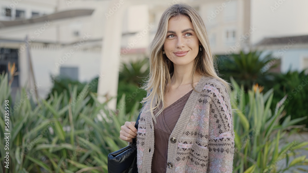 Young blonde woman smiling confident standing at park