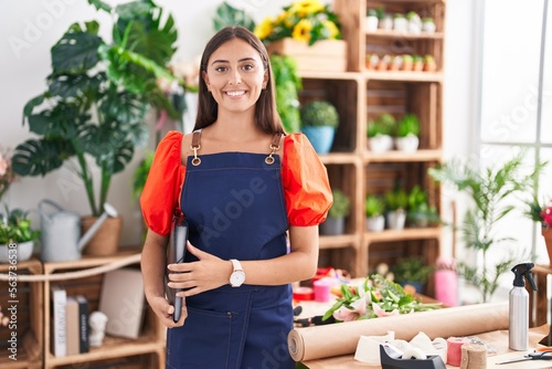 Young beautiful hispanic woman florist smiling confident holding binder at florist