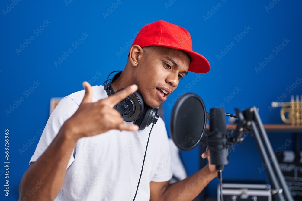 Obraz premium Young latin man artist singing song reading notebook at music studio