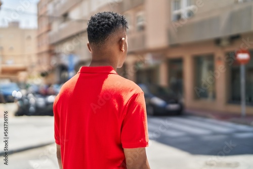 Young latin man standing on back view at street