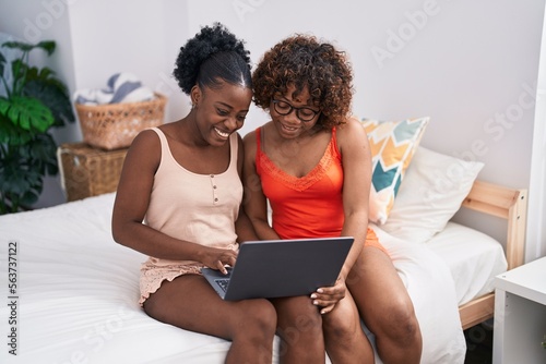 African american women mother and daughter using laptop at bedroom