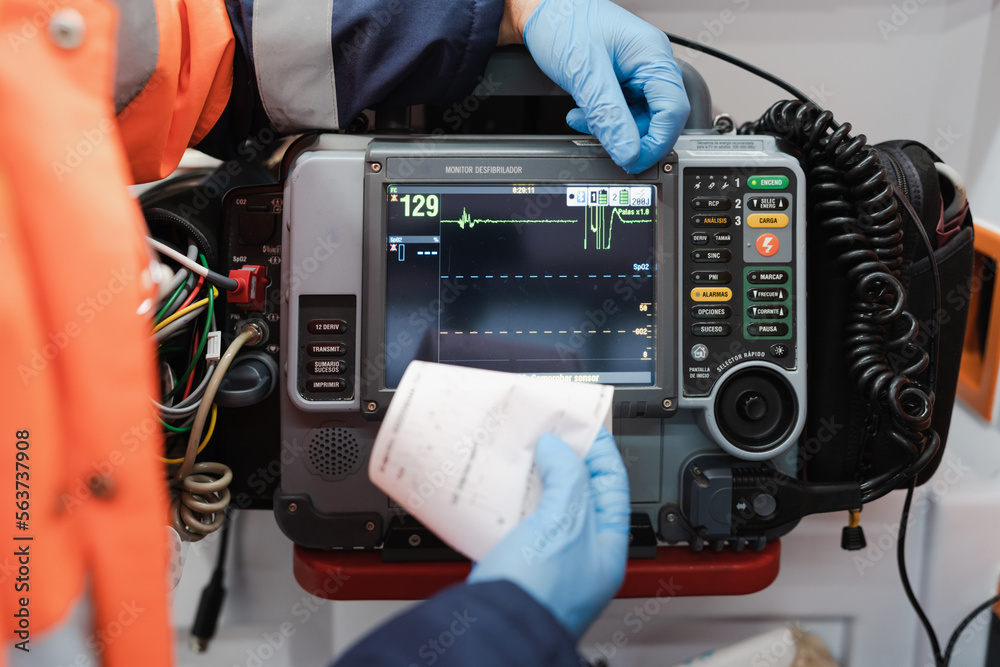 Close-up of a unrecognizable doctor using a defibrillator monitor - obrazy, fototapety, plakaty 