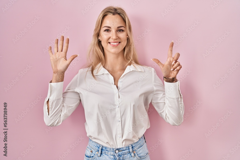 Young caucasian woman wearing casual white shirt over pink background showing and pointing up with fingers number seven while smiling confident and happy. Young caucasian woman wearing casual white shirt over pink background showing and pointing up with fingers number seven while smiling confident and happy.