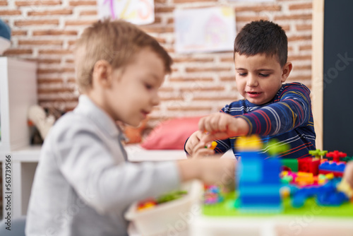 Two kids playing with construction blocks sitting on table at kindergarten