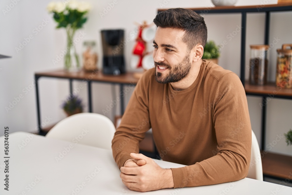 Young hispanic man smiling confident sitting on table at home Young hispanic man smiling confident sitting on table at home
