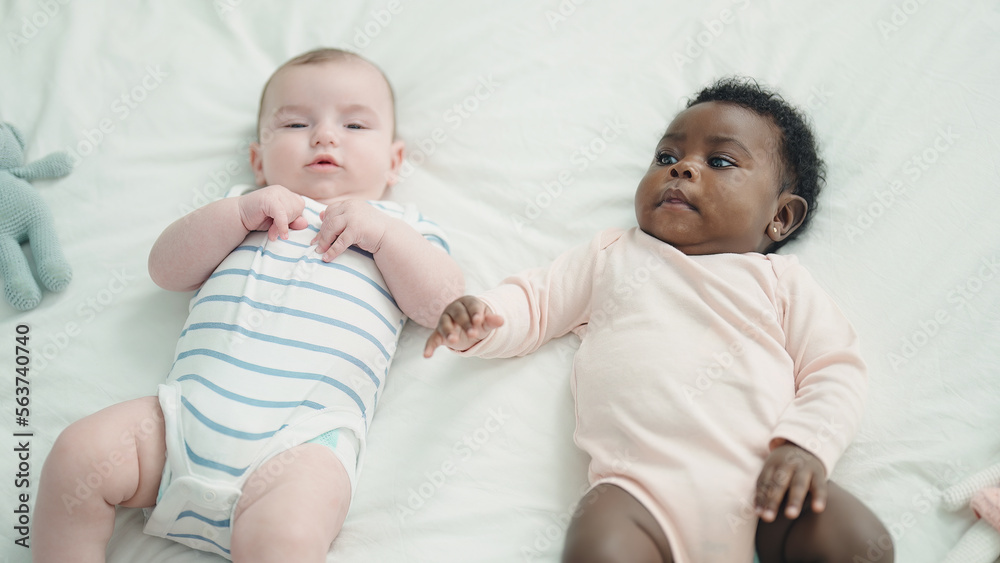 Two adorable babies lying on bed at bedroom Two adorable babies lying on bed at bedroom