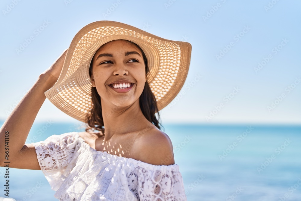Young african american woman tourist smiling confident wearing summer hat at seaside