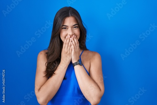 Принти на полотні Hispanic woman standing over blue background laughing and embarrassed giggle cov