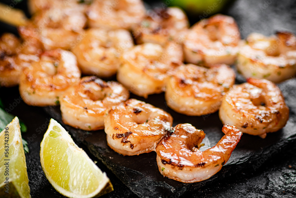 Grilled shrimp on a stone board with pieces of lime. Grilled shrimp on a stone board with pieces of lime.