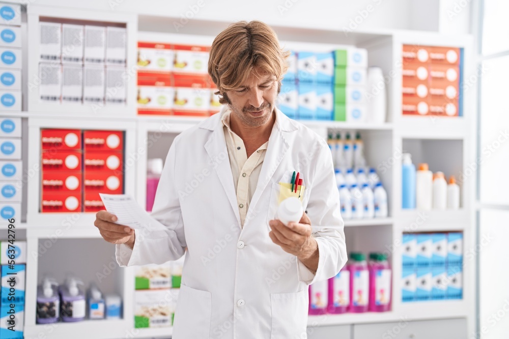 Young man pharmacist holding pills bottle and prescription at pharmacy