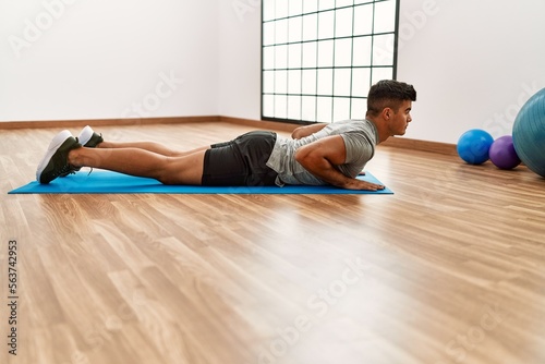 Young hispanic man stretching at sport center