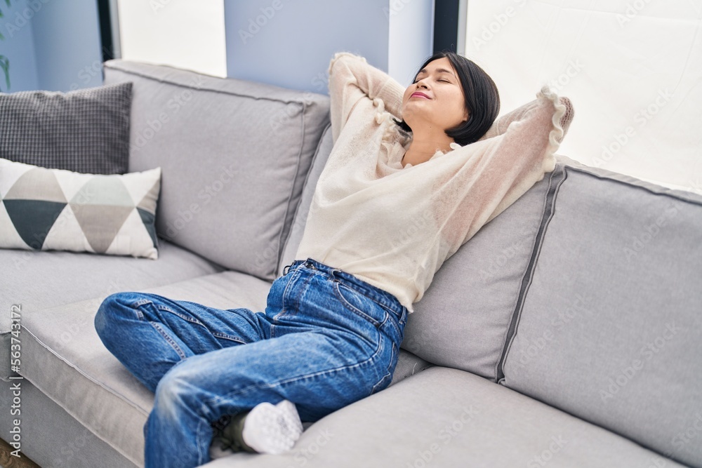 Young chinese woman relaxed with hands on head sitting on sofa at home Young chinese woman relaxed with hands on head sitting on sofa at home