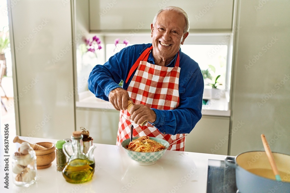 Senior man smiling confident pouring pepper on spaghetti at kitchen Senior man smiling confident pouring pepper on spaghetti at kitchen